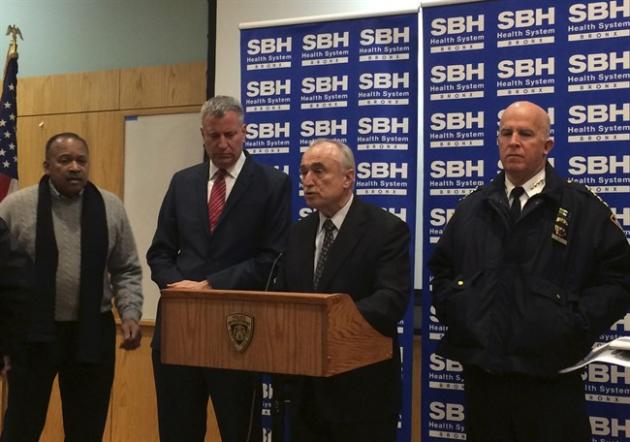 New York City Mayor Billl de Blasio, second left, stands by as Police Commissioner William Bratton, second right, speaks at a news conference at St. Barnabas Hospital in the Bronx section of New York City after two New York City police officers were shot. The two officers responding to a robbery in the Bronx were shot and wounded Monday night, and a manhunt was underway for at least two suspects, authorities said. The officers were taken to the hospital with non-life threatening injuries. (AP Photo/Tom McElroy)