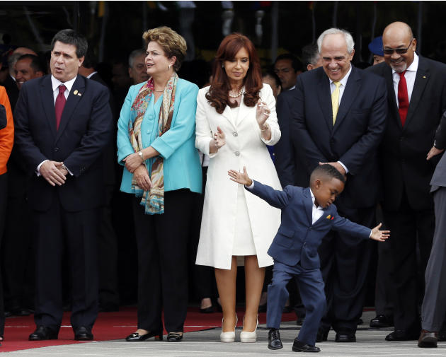 En esta imagen del 5 de diciembre de 2014, un niño actúa en la inauguración de la nueva sede de UNASUR, ante la presidenta argentina Cristina Fernández (en el centro), el secretario general de UNASUR,