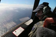 A Royal New Zealand Air Force pilot looks out of the window of his aircraft while searching for wreckage of the missing Malaysia Airlines flight MH370 over the Indian Ocean, on March 31, 2014