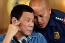 Philippine President Rodrigo Duterte listens as PNP   Director General Ronald Dela Rosa whispers to him, during a late night news   conference at the presidential palace in Manila