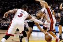 Tony Parker, de los Spurs de San Antonio pasa entre Dwyane Wade y Goran Dragic, del Heat de Miami, durante el partido del martes 31 de marzo de 2015 (AP Foto/Joe Skipper)