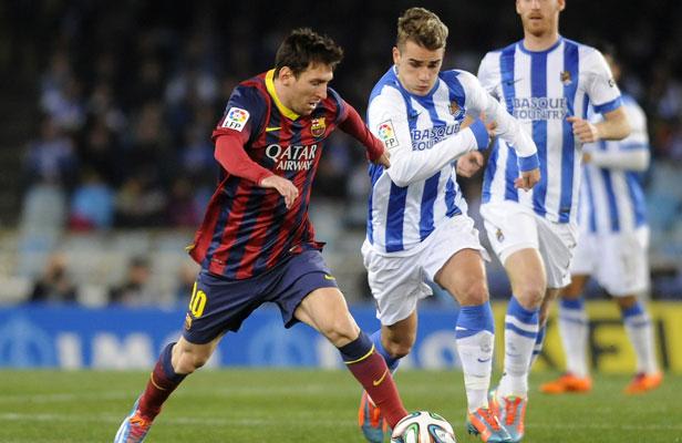 L'attaquant français de la Real Sociedad Antoine Griezmann contre Lionel Messi et le FC Barcelone, le 22 février 2014, à San Sebastien., ANDER GILLENEA / AFP