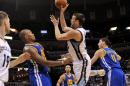 El español Marc Gasol, pívot de los Grizzlies de Memphis, dispara entre Marreese Speights y Klay Thompson, de los Grizzlies de Memphis, en el encuentro del martes 16 de diciembre de 2014 (AP Foto/Brandon Dill)