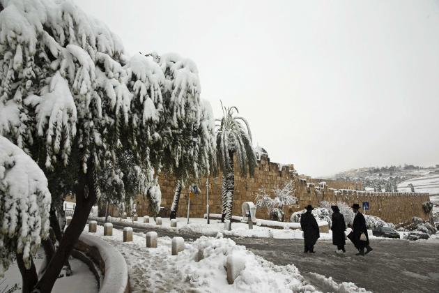 Ultra-Orthodox Jewish men stand on a snow-covered street outside Jerusalem's Old City