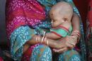 A woman holding her baby sits in a street at a slum   in Mumbai