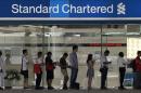 People queue up outside a Standard Chartered Bank   branch before operation hours at the central business district in Singapore