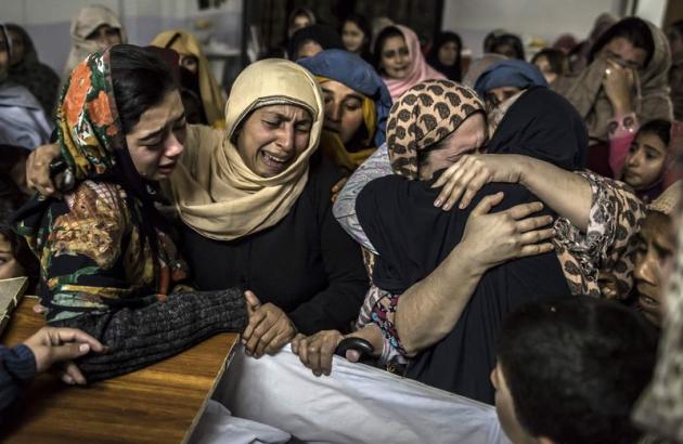 Femmes auprès de la dépouille d'un étudiant de 15 ans tué dans l'attaque d'une école gérée par l'armée à Peshawar, près de la frontière afghane dans le nord-ouest du Pakistan. Au moins 132 élèves et neuf enseignants ont été tués dans l'attaque perpétrée par des taliban lourdement armés. /Photo prise le 16 décembre 2014/REUTERS/Zohra Bensemra