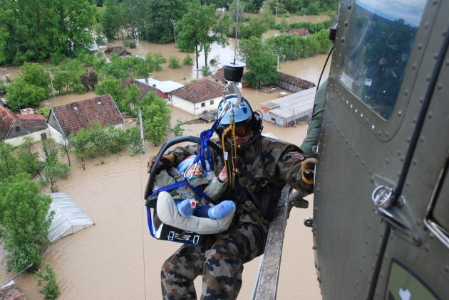 In this picture taken on Saturday, May 17, 2014, and made available Tuesday May 20, 2014 a Slovenian army helicopter team rescues a small baby by winching the baby carrier into the helicopter over the