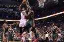 El base de los Raptors de Toronto DeMar DeRozan (centro) dispara frente a la marca de Larry Sanders de los Bucks de Milwaukee durante el partido jugado el viernes 21 de noviembre de 2014. (Foto AP/The Canadian Press, Frank Gunn)