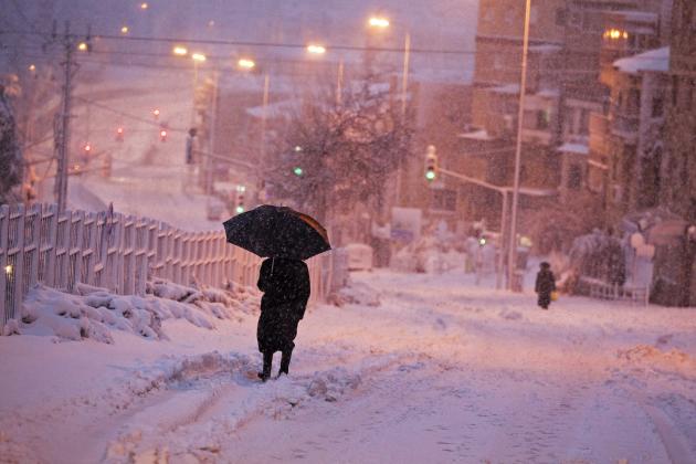 An ultra-Orthodox Jewish man walks on a snow-covered street early morning near Jerusalem's Mea Shearim neighbourhood