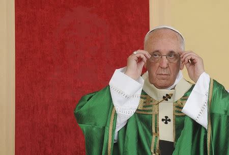 Pope Francis adjusts his glasses in front of his chair, which has an image of the Shroud of Turin woven into the red fabric, as he leads a mass during a two-day pastoral visit in Turin, Italy, June 21, 2015. REUTERS/Giorgio Perottino