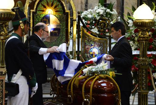 El vicepresidente uruguayo Raúl Sendic (D) despliega el paballón nacional sobre el ataúd que contiene los restos mortales del escritor Eduardo Galeano, durante el velatorio celebrado en la sede del Congreso en Montevideo, el 15 de abril de 2015