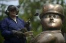 Un hombre trabaja junto a una escultura del colombiano Fernando Botero en el parque Botero, en Medellin, Colombia, el 13 de noviembre de 2013