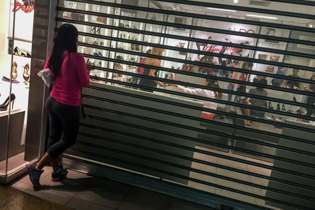 ACOMPAÑA CRÓNICA: VENEZUELA ECONOMÍA. CAR05. CARACAS (VENEZUELA), 13/11/2014.- Una mujer observa desde entrada de una tienda de ropa en un centro comercial hoy, jueves 13 de noviembre del 2014, en Caracas (Venezuela). Una multitud se concentra frente a la entrada de una tienda de ropa en un concurrido centro comercial en Caracas con una única misión: comprar con los "precios justos" que establece el Gobierno venezolano previo a la temporada navideña. La escena se repite en un trío de locales más, todas ellas franquicias de la textil española Inditex, que reapareció con nueva mercancía y colmó sus entradas con decenas de venezolanos con necesidades distintas, o simple curiosidad, ansiosos por gozar de los beneficios que ofrecen los controles gubernamentales sobre los precios. EFE/Miguel Gutiérrez
