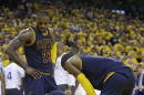 Un médico revisa al delantero de los Cavaliers de Cleveland, Kevin Love, abajo, mientras sus compañeros LeBron James (23) y Kyrie Irving observan, durante la primera mitad del Juego 2 de la final de la NBA contra los Warriors de Golden State en Oakland, California, el domingo 5 de junio de 2016. (AP Foto/Marcio Jose Sanchez)