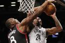 El pívot de los Raptors de Toronto, Bizmack Biyombo, le comete una falta al base de los Nets de Brooklyn, Rondae Hollis-Jefferson, en la segunda mitad del juego del miércoles 13 de abril de 2016 en Nueva York. (Foto AP/Kathy Willens)