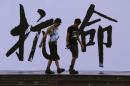 Pro-democracy activists walk past a backdrop with Chinese characters that read "disobedience" in Hong Kong