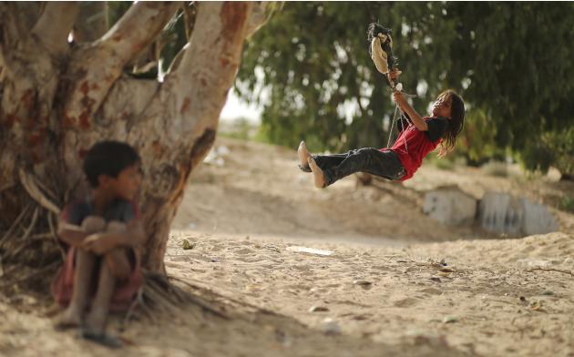 A Palestinian girl swings on a rope tied on a tree at a former Jewish settlement in Khan Younis in the southern Gaza Strip