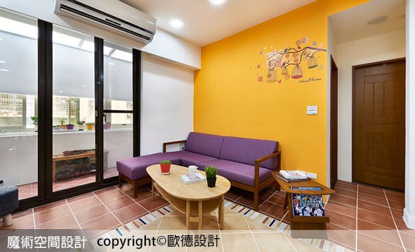 客廳沙發後方牆壁則塗成暖黃色，並飾以局部可愛壁貼，散發赤子之心的純真氣息。優渥實木的沙發與茶几營造優雅大器的氛圍。