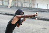 A masked Palestinian protester uses a slingshot to throw stones during clashes with Israeli security forces in the occupied West Bank city of Hebron, on October 21, 2015