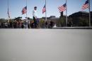People wait in line as U.S. flags fly at half-staff   at the Washington Monument on the National Mall in Washington