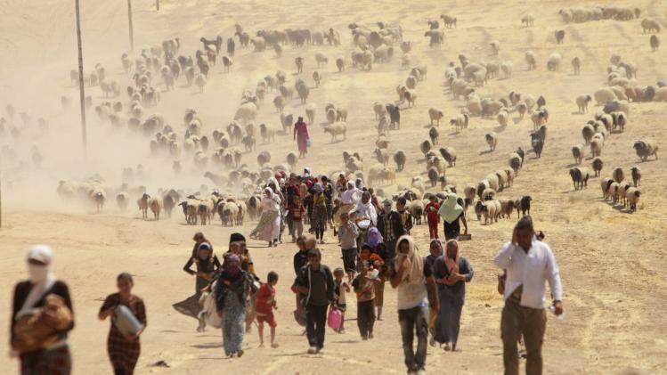 Displaced people from minority Yazidi sect, fleeing violence from forces loyal to ISIL in Sinjar town, walk toward the Syrian border, on outskirts of Mount Sinjar.