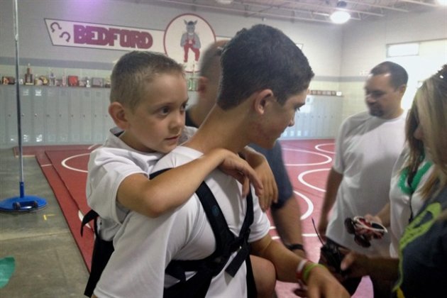 Hunter Gandee, 14, holds his brother Braden Gandee, 7, in a harness on his back on Saturday, June 7, 2014, in Temperance, Mich. Hunter set out on a 40-mile trek on Saturday with his brother strapped to his back, hoping to raise awareness about the muscular condition, Cerebral Palsy Swagger, that prevents the younger boy from being able to walk without help. (AP Photo/Detroit Free Press, Eric D. Lawrence) DETROIT NEWS OUT; NO SALES