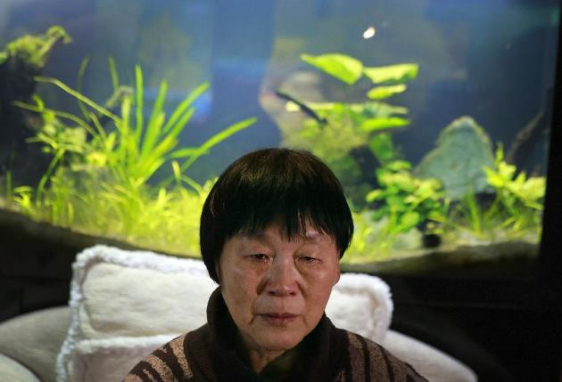 In this Sunday, Dec. 28, 2014 photo, Dai Shuqin, whose sister was aboard Malaysia Airlines Flight 370 that went missing on March 8, 2014, weeps as she watches TV news about missing AirAsia Flight 8501, during a year-end gathering with others at a house in Beijing, China. Images of bodies and wreckage floating in Indonesian waters gave relatives of those lost aboard AirAsia Flight 8501 anguish and grief, but they also provided the answers that other families have sought in vain for nearly 10 months. “We have been living in anxiety, fear and hate, and our lives have been utterly messed up, but we as ordinary people are unable to do anything,” said Dai. (AP Photo/Andy Wong)