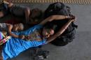 A passenger sleeps along with her children at a   railway station on a hot summer day in Allahabad