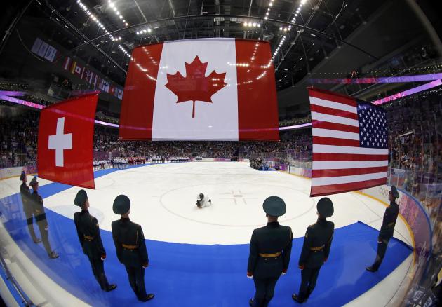 The flags of Canada [C), the U.S. and Switzerland (L) are raised after the women's ice hockey gold medal game at the Sochi 2014 Winter Olympic Games February 20, 2014. Canada won their fourth consecutive Olympic women's ice hockey gold medal with a wild 3-2 overtime win over the United States at the Sochi Games on Thursday. Switzerland beat Sweden earlier on Thursday to claim the bronze. REUTERS/Mark Blinch (RUSSIA - Tags: SPORT ICE HOCKEY OLYMPICS)