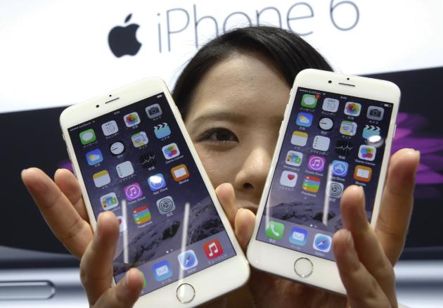 A customer shows off the new Apple iPhone 6 and 6 Plus at a store in Tokyo Friday, Sept. 19, 2014. (AP Photo/Shizuo Kambayashi)