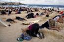 A group of around 400 demonstrators participate in a protest by burying their heads in the sand at Sydney's Bondi Beach