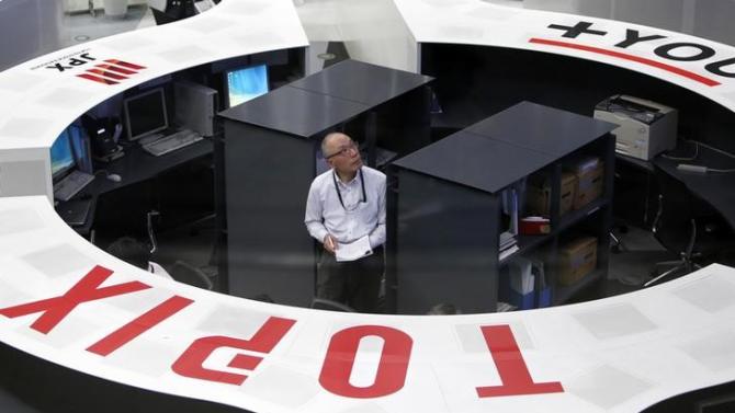 An employee of the Tokyo Stock Exchange looks at a stock quotation board as he works at the bourse at TSE in Tokyo