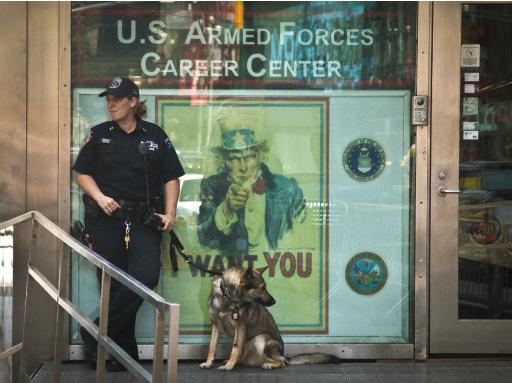 Un oficial de contraterrorismo de la policía de Nueva York monta guardia con un perro en una estación de reclutamiento militar en la plaza Times Square el viernes 17 de julio de 2015 en Nueva York. La seguridad de centros de reservistas y de reclutamiento del ejército será revisada tras el letal tiroteo ocurrido en Tennessee. (Foto AP/Bebeto Matthews)