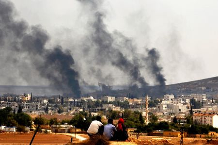 Kurdish refugees from Kobani watch as thick smoke covers the Syrian town of Kobani during fighting between Islamic State and Kurdish Peshmerga forces, as seen from the Mursitpinar crossing on the Turkish-Syrian border in Sanliurfa province October October 26, 2014. REUTERS/Yannis Behrakis