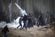 Un manifestante palestino devuelve una granada de gas lanzada por fuerzas de seguridad israelíes durante las protestas a restricciones impuestas por Israel a la Mezquita de Al Aqsa en Jerusalén, en el retén Qalandia cerca de Ramalá, Cisjordania, viernes 21 de noviembre de 2014. (AP Foto/Majdi Mohammed)