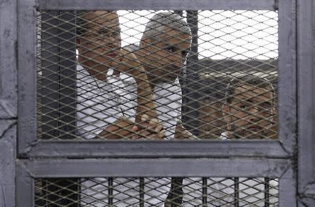 Al Jazeera journalists (L-R) Peter Greste, Mohammed Fahmy and Baher Mohamed stand behind bars at a court in Cairo June 1, 2014. REUTERS/Asmaa Waguih