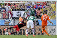 Mexico's goalkeeper Guillermo Ochoa can not stop a penalty shot by Netherlands' Klaas-Jan Huntelaar to score his side's second and winning goal during the World Cup round of 16 soccer match between the Netherlands and Mexico at the Arena Castelao in Fortaleza, Brazil, Sunday, June 29, 2014. The Netherlands defeated Mexico 2-1. (AP Photo/Felipe Dana)