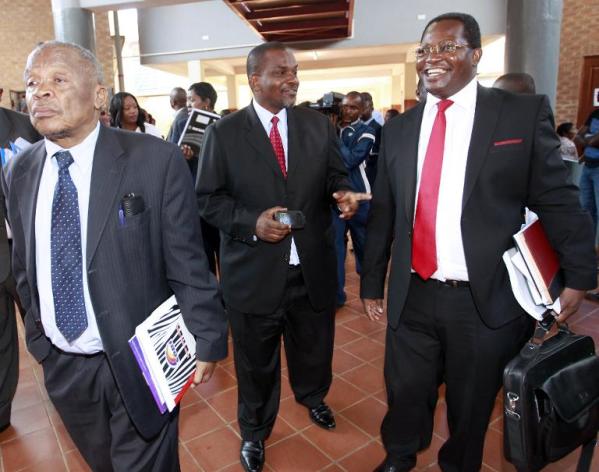 Zambia's Director of Public Prosecutions Mutembo Nchito (C) chats with former president Rupiah Banda’s lawyers Erick Silwamba (R) and Patrick Mvunga (L) as they leave the Lusaka magistrates' court on March 26, 2013