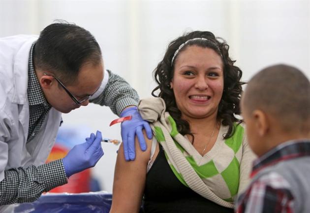 FILE- In this Nov. 27, 2014 file photo, Walgreens pharmacist Chris Nguyen gives a free flu shot to Sandra Bazaldua in Houston, Texas. The flu vaccine may not be very effective this winter, according to U.S. health officials who worry this may lead to more serious illnesses and deaths. The Centers for Disease Control and Prevention issued an advisory to doctors about the situation Wednesday, Dec. 3, 2014. (AP Photo/Houston Chronicle, Gary Coronado, File)