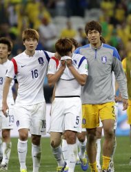 South Korea's Kim Young-gwon, center, is comforted by his teammates Ki Sung-yueng, left, and goalkeeper Lee Bum-young, right, after the group H World Cup soccer match between South Korea and Belgium at the Itaquerao Stadium in Sao Paulo, Brazil, Thursday, June 26, 2014. Belgium beat South Korea 1-0 to top Group H of the World Cup. South Korea was eliminated. (AP Photo/Felipe Dana)