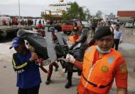 Rescue team members walk as they carry the wreckage of a seat of the AirAsia Flight QZ8501 airliner at Kumai port in Pangkalan Bun, January 19, 2015. REUTERS/Beawiharta