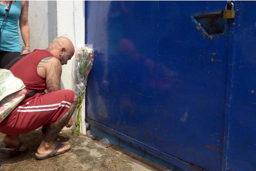 A foreign man lays flowers as he prays in front of a house where a Dutch woman was found stabbed in Phnom Penh on April 30, 2014