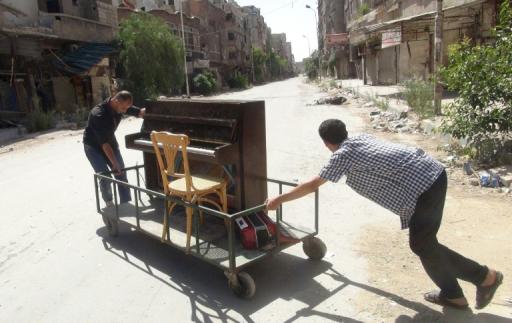 File picture shows Aeham al-Ahmad, a former resident of Damascus' Yarmuk Palestinian refugee camp, being helped by a friend to push his piano along a the street in the southern Damascus suburb