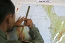 An Indonesian Air Force officer draws a flight pattern flown earlier in a search operation for the missing Malaysia Airlines Boeing 777, during a post-mission briefing at Suwondo air base in Medan, North Sumatra, Indonesia, Thursday, March 13, 2014. The hunt for the missing jetliner has been punctuated by false leads since it disappeared with 239 people aboard about an hour after leaving Kuala Lumpur for Beijing early Saturday. (AP Photo/Binsar Bakkara)