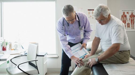  Doctor checking a man's knee | Hero Images/Getty Images