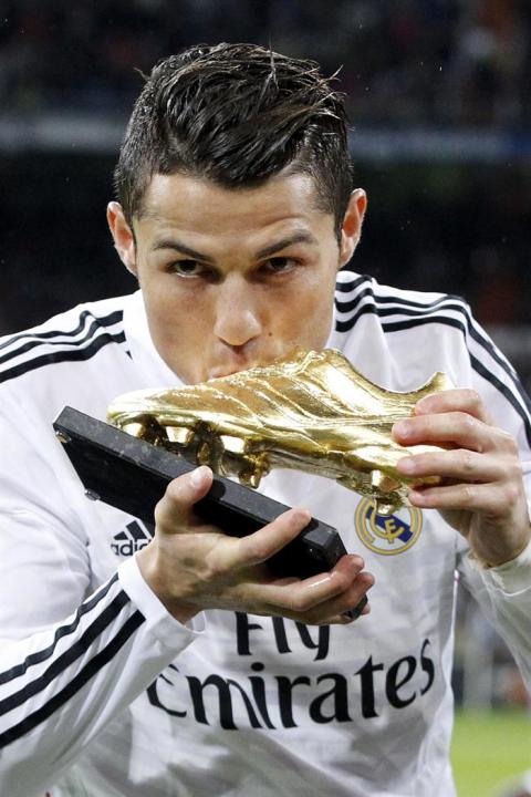 GRA304. MADRID, 08/11/2014.- El delantero portugués del Real Madrid Cristiano Ronaldo besa la Bota de Oro 2013 que recibió el miércoles, momentos antes del partido de la undécima jornada de liga de Pr