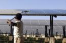 A worker cleans photovoltaic solar panels inside a solar power plant at Raisan village near Gandhinagar