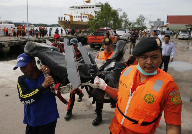 Rescue team members walk as they carry the wreckage of a seat of the AirAsia Flight QZ8501 airliner at Kumai port in Pangkalan Bun, January 19, 2015. The flight lost contact with air traffic control in bad weather on December 28, less than halfway into a two-hour flight from the Indonesian city of Surabaya to Singapore. REUTERS/Beawiharta (INDONESIA - Tags: DISASTER TRANSPORT TPX IMAGES OF THE DAY)