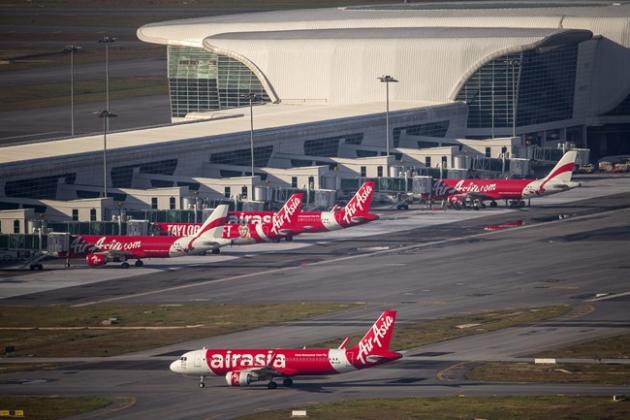 CORRECTS NUMBER OF PASSENGERS ON BOARD - In this Nov 26, 2014 photo, AirAsia Airbus A320-200 passenger jets are seen on the tarmac at low cost terminal KLIA2 in Sepang, , Malaysia. An AirAsia plane with 162 people on board lost contact with ground control on Sunday, Dec. 28, 2014, while flying over the Java Sea after taking off from a provincial city in Indonesia for Singapore, and search and rescue operations were underway. The planes in this photo are not the plane that went missing while flying from Indonesia to Singapore but one of the same models. (AP Photo/Vincent Thian)